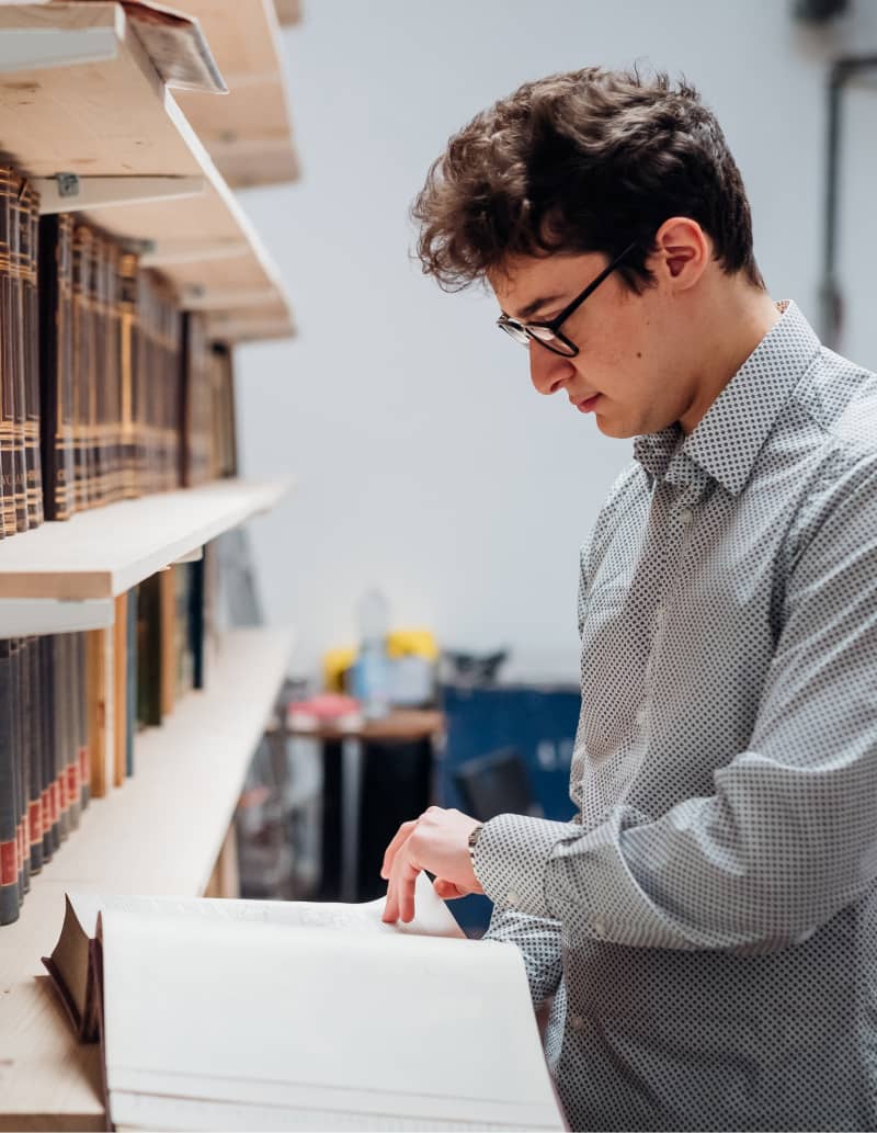 man looking at a book in a library